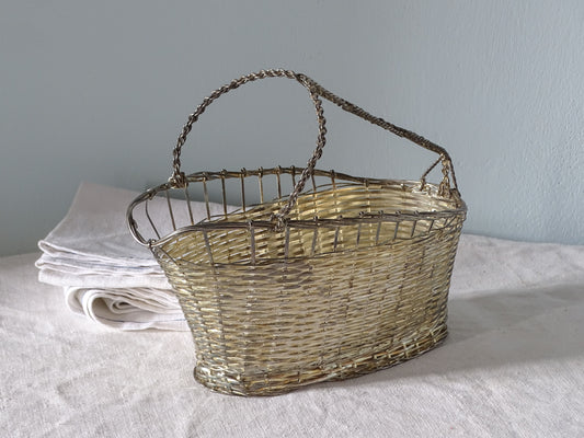 A French vintage woven metal basket bottle carrier with a twisted metal handle.