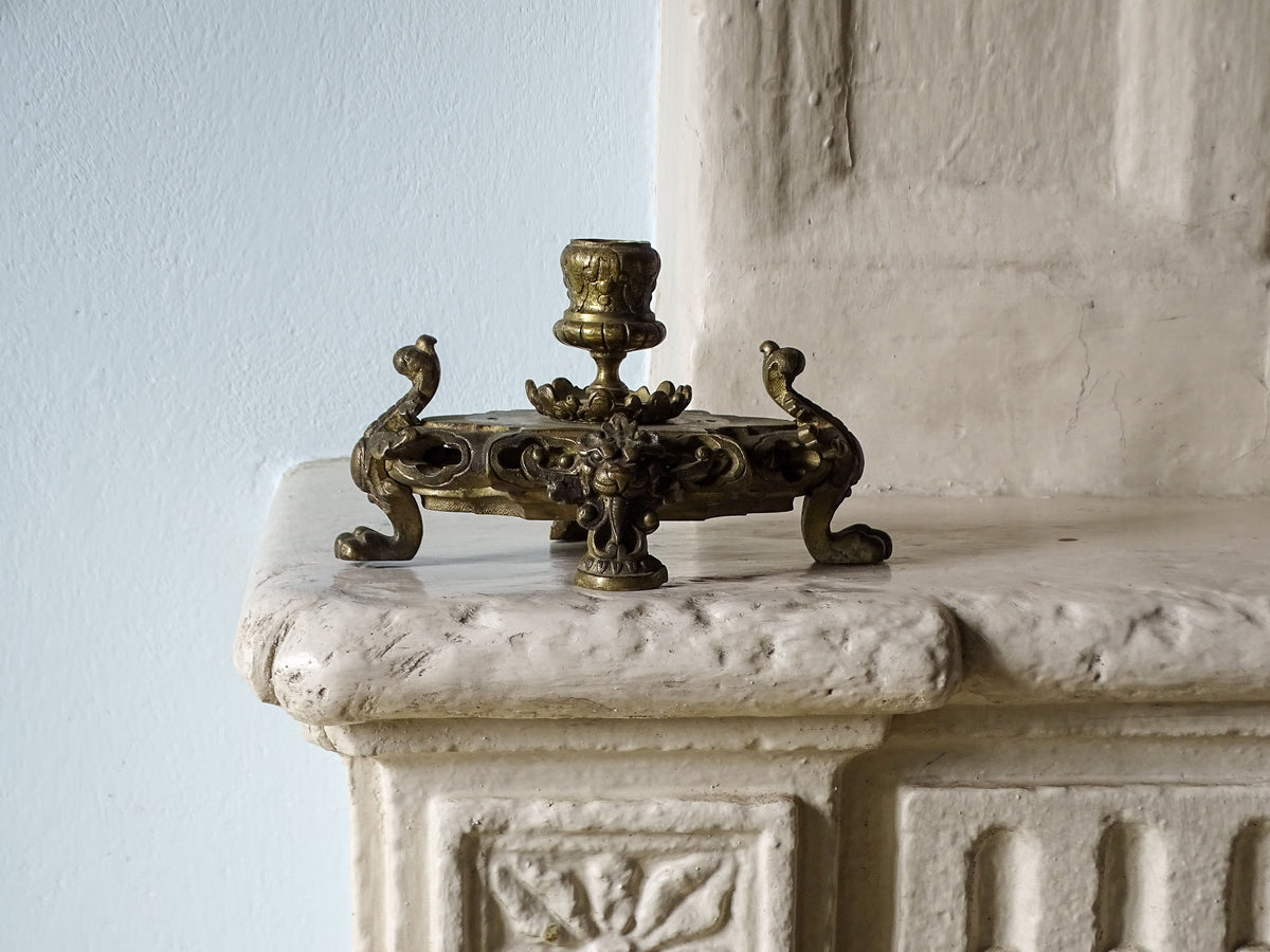 French antique brass candle holder, pictured on a country house fireplace