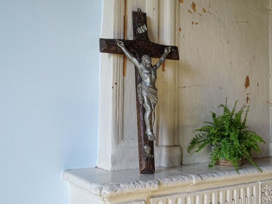 French antique wooden crucifix with silver metal corpus of Jesus Christ, pictured on a country house fireplace with a potted fern