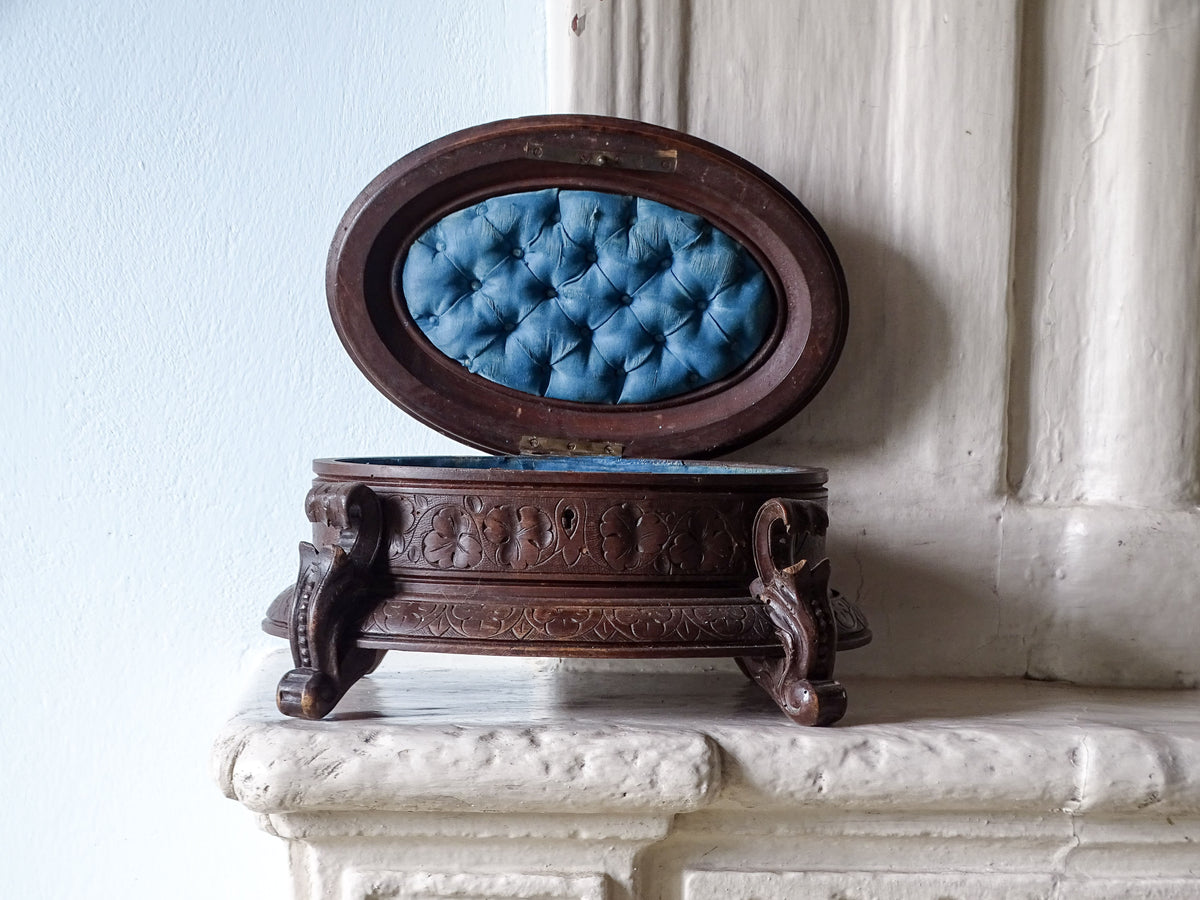 Antique Swiss black forest box with blue interior on a country house fireplace next to pale blue wall