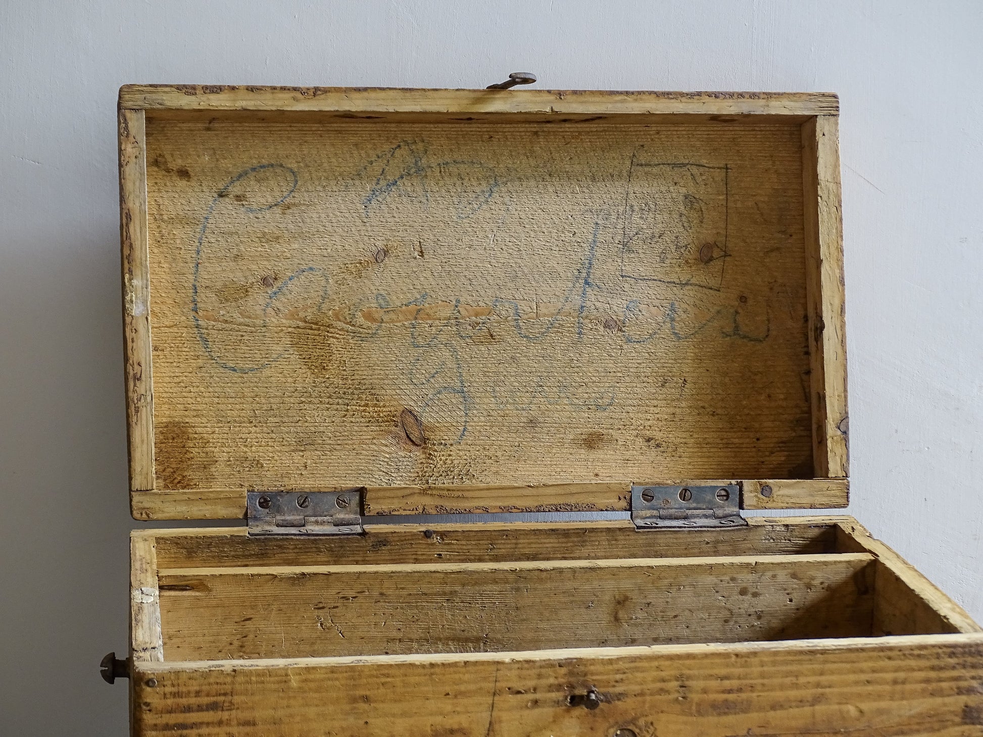 Open French wooden storage box showing divided interior and handwritten markings inside lid