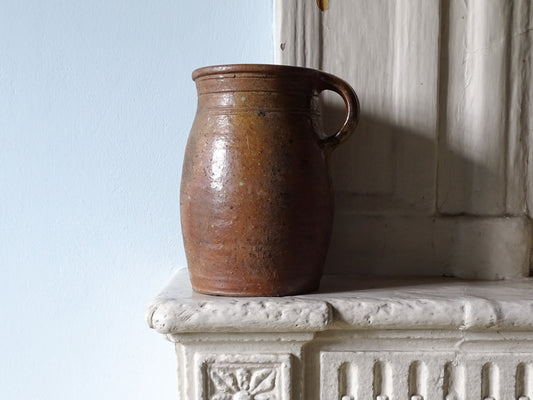 French antique earthenware jug with brown glaze displayed on a country house fireplace