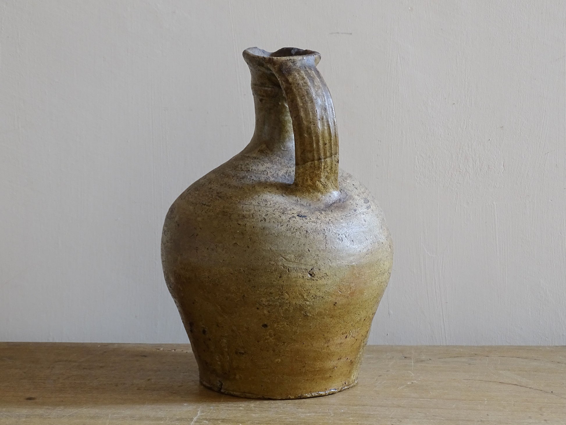 Rustic French earthenware water jug with worn glaze and pouring lip