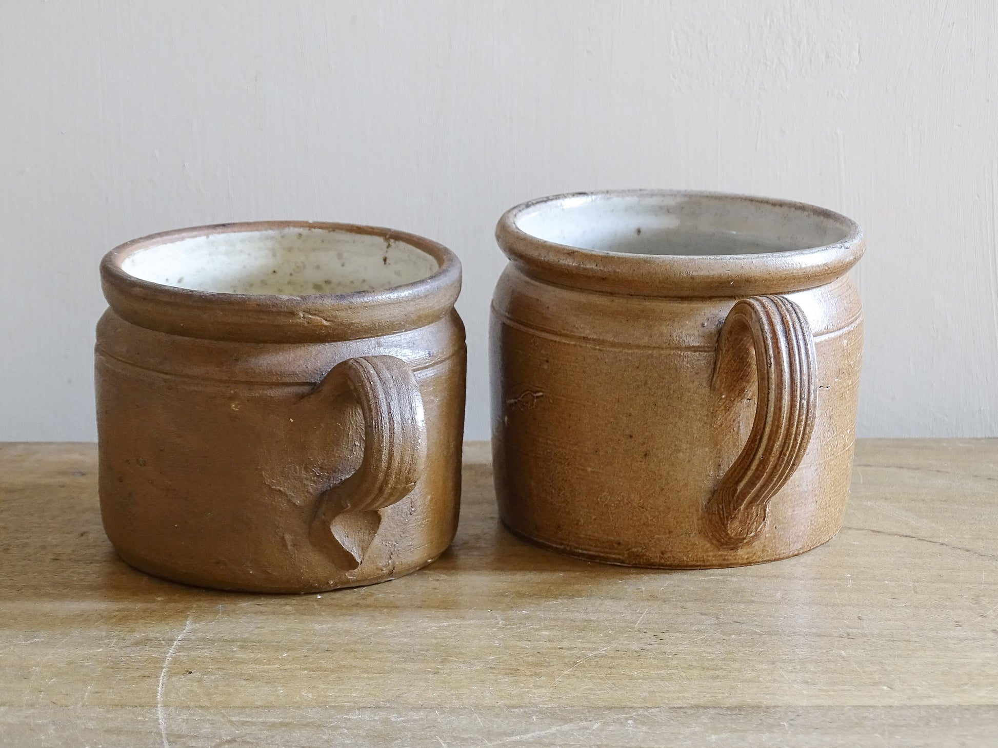 Rustic brown French stoneware cups with curved ribbed handles and aged patina