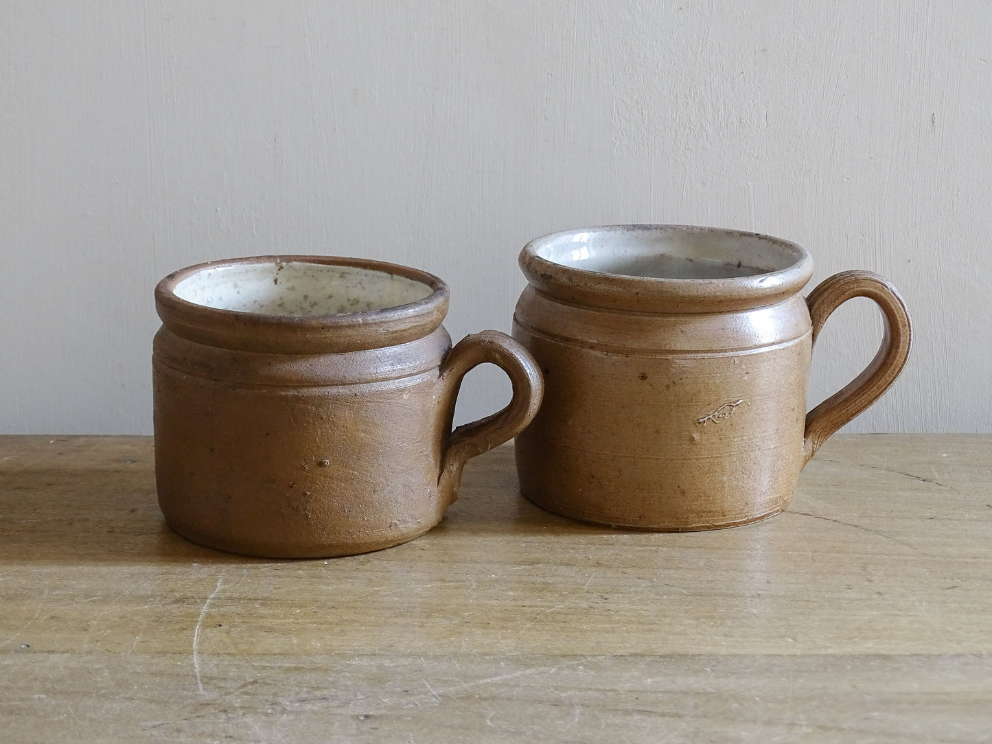 Rustic brown French stoneware cups with curved ribbed handles and aged patina