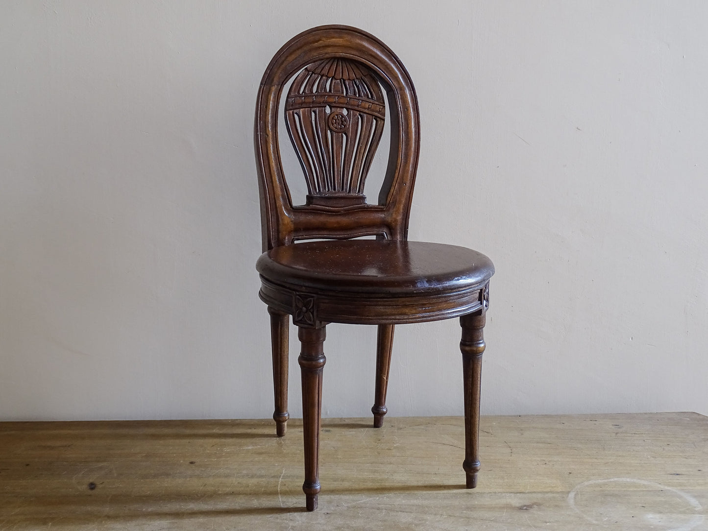 Small antique display chair with carved balloon motif and oval backrest
