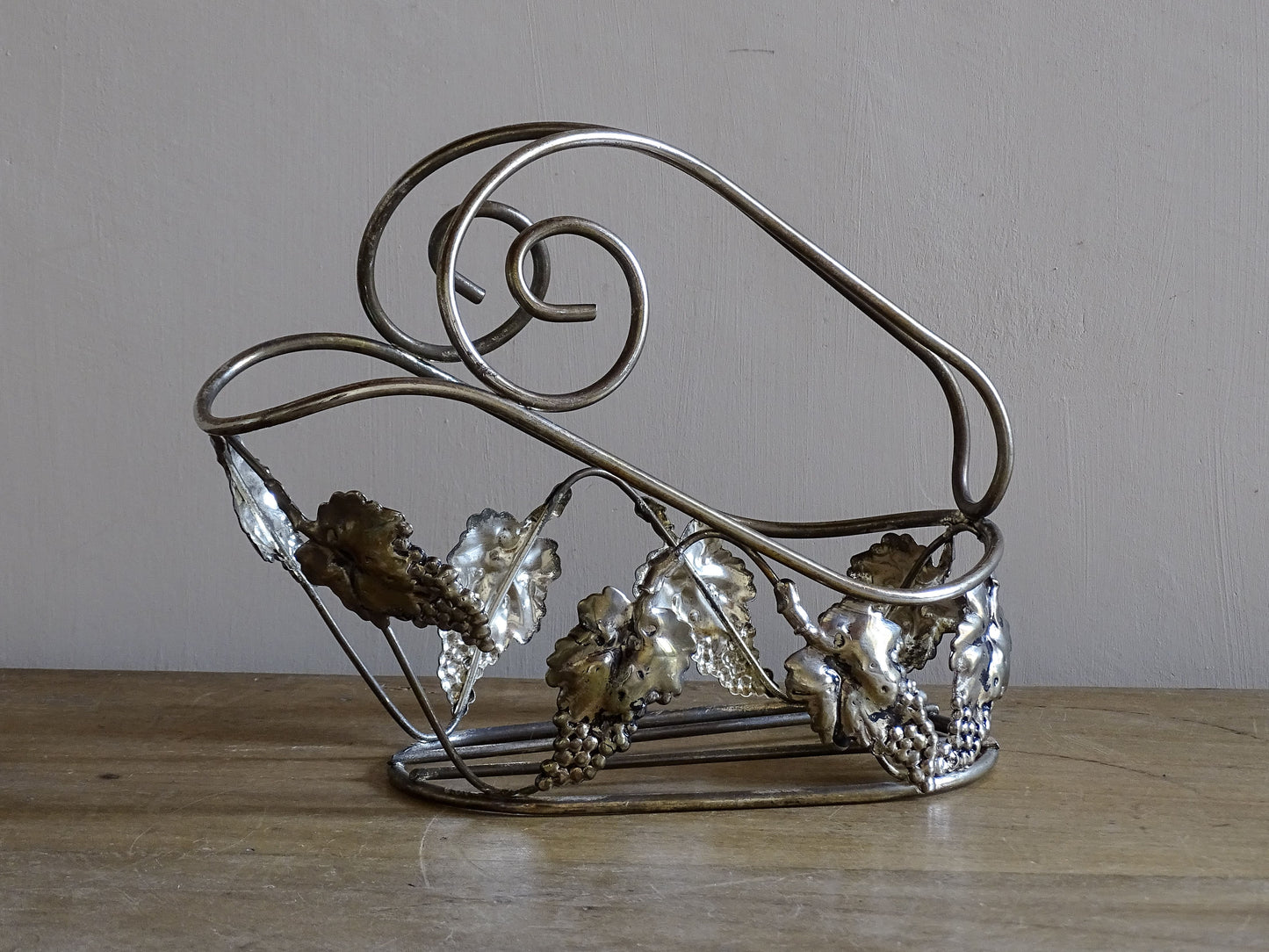 Silvered metal French vintage wine bottle stand displayed on a rustic wooden table