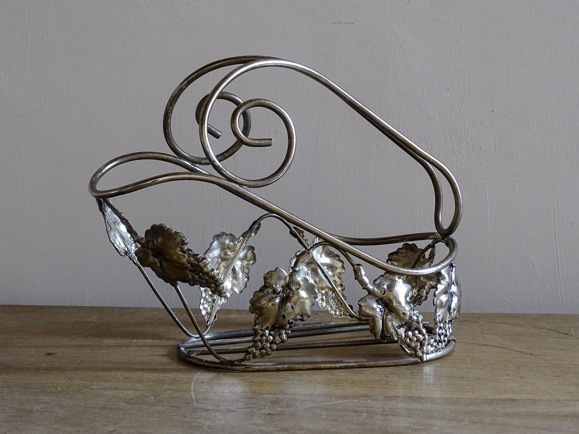 Silvered metal French vintage wine bottle stand displayed on a rustic wooden table