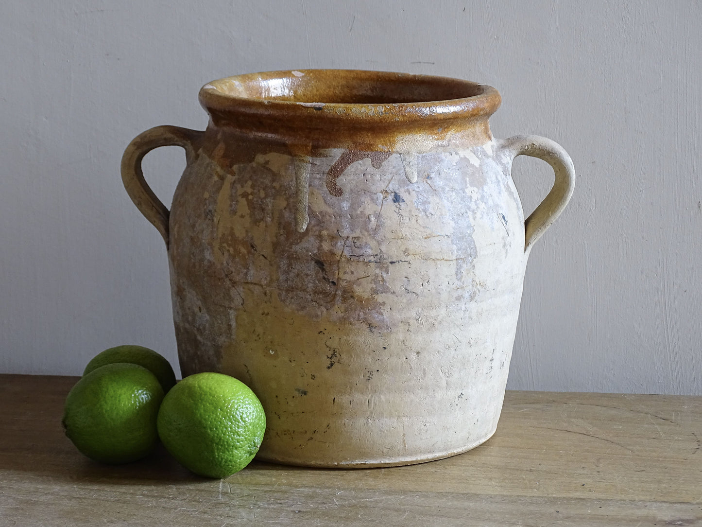 Vintage French ceramic confit pot with honey yellow glazed interior and worn cream exterior