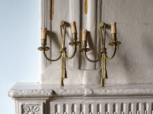 Pair of French antique wall light sconces with tassel design and twin arms, displayed on a French country house fireplace
