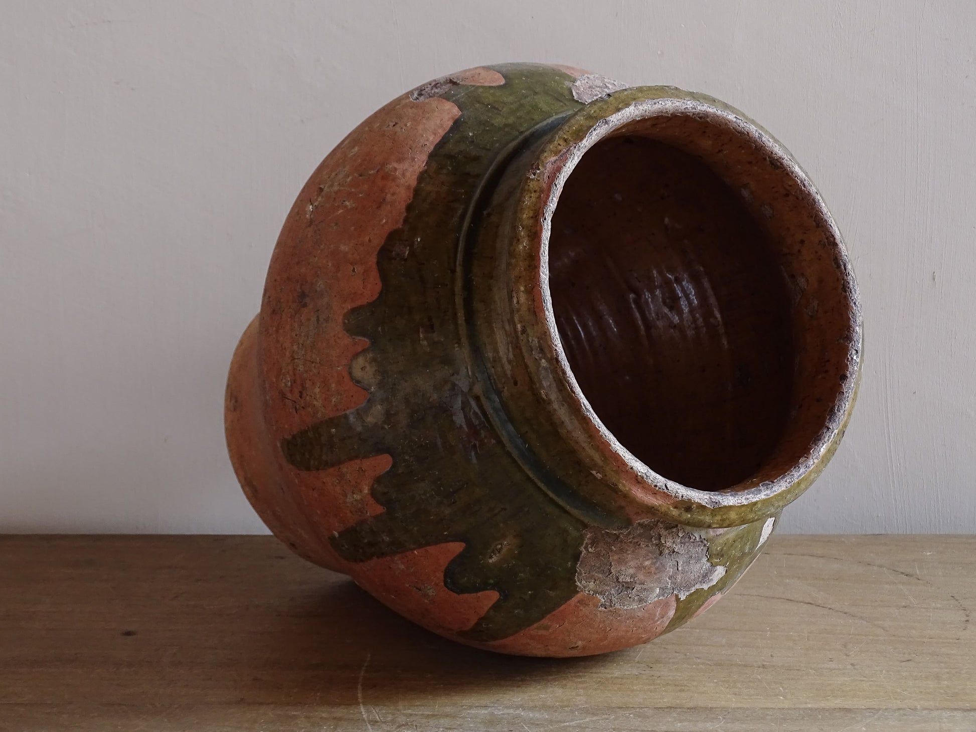 Decorative French earthenware vase with green drip glaze and timeworn surface