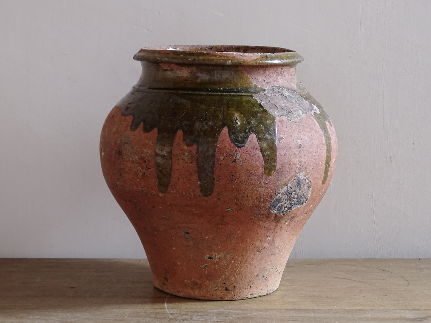 Antique French earthenware storage jar with aged terracotta surface and green glaze