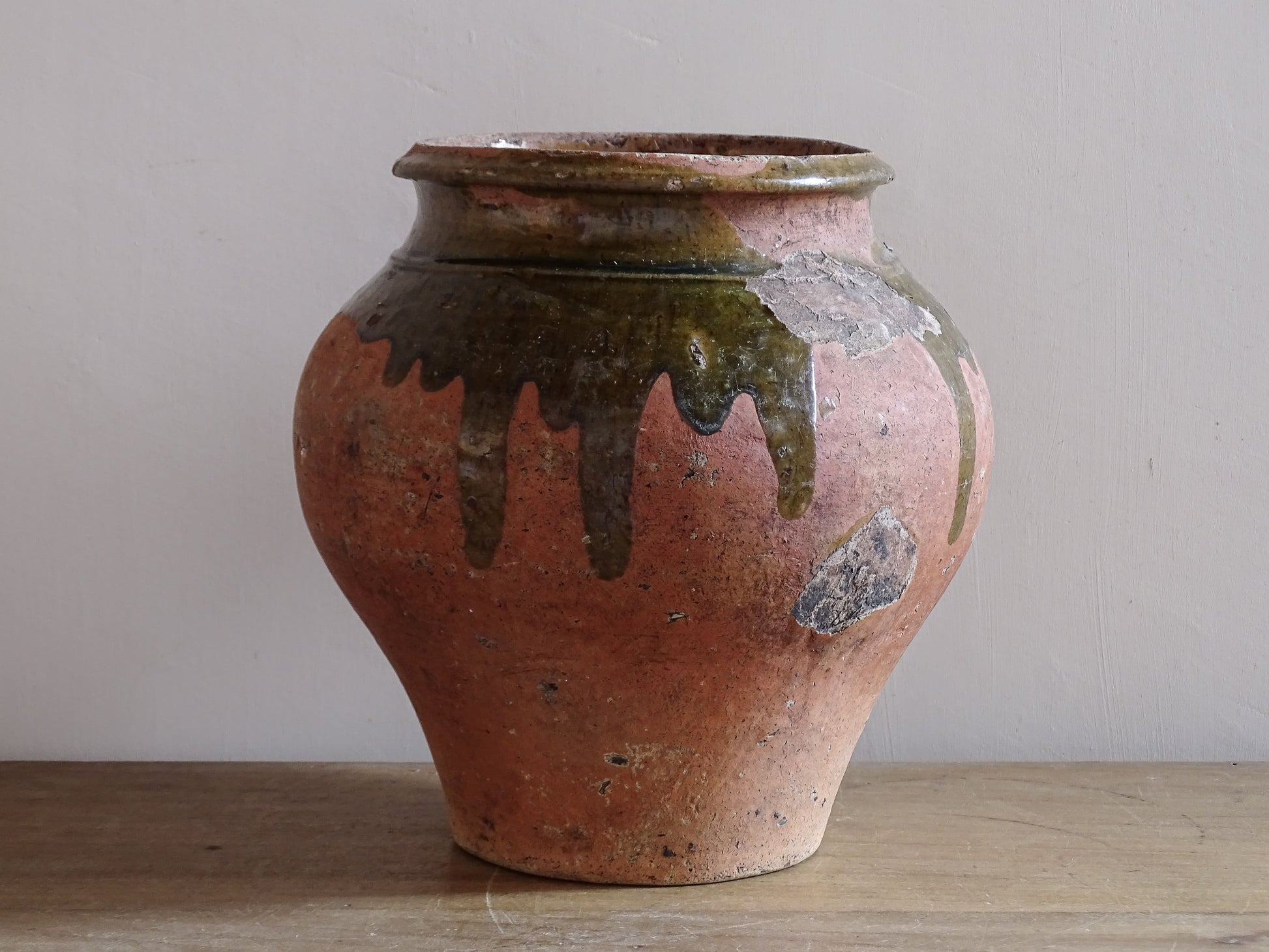 Antique French earthenware storage jar with aged terracotta surface and green glaze