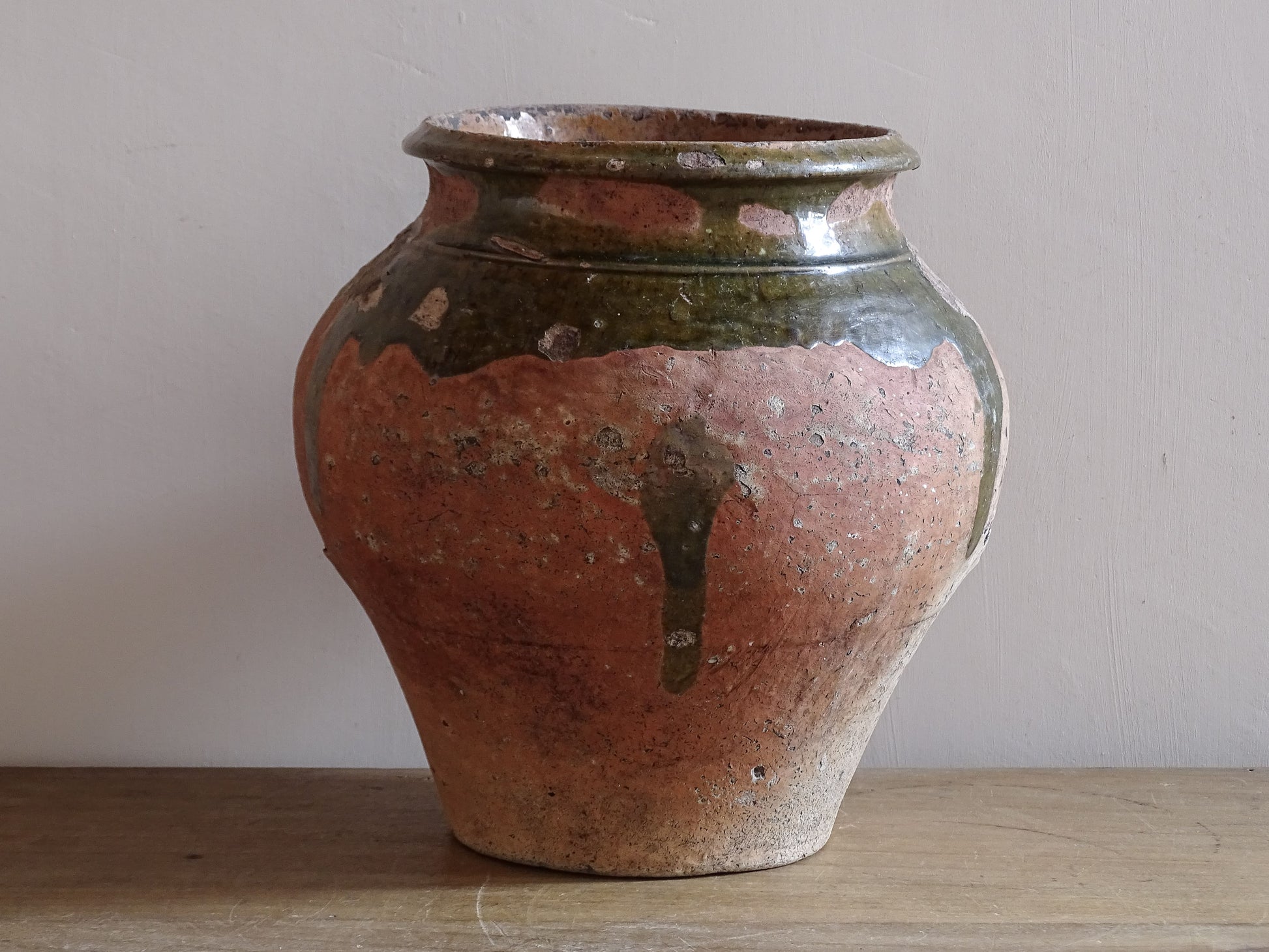 Provincial French pottery vessel with green glaze over warm terracotta clay