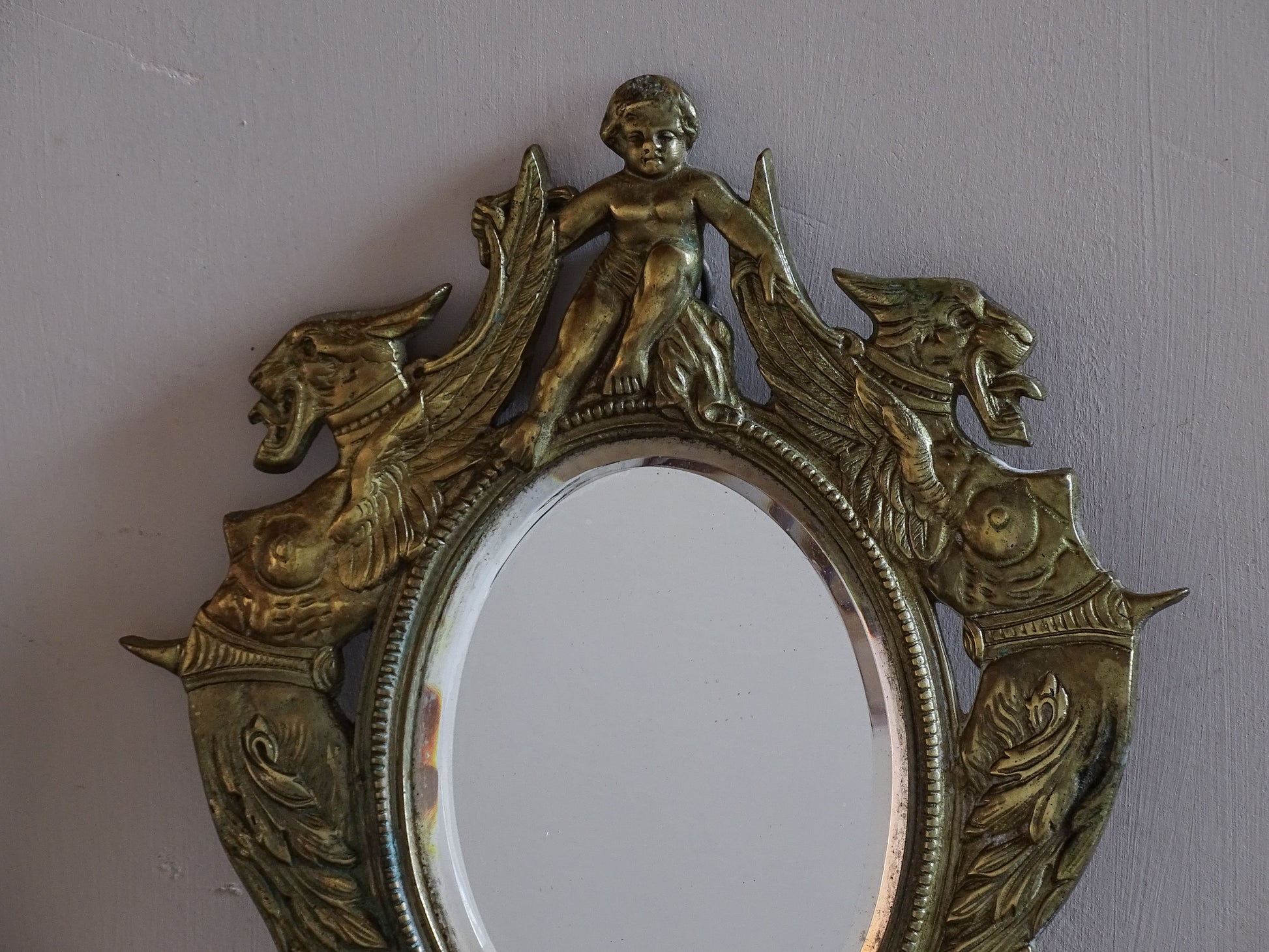 French Napoleon III gilt brass mirror sconce with winged griffins and oval mirror.
