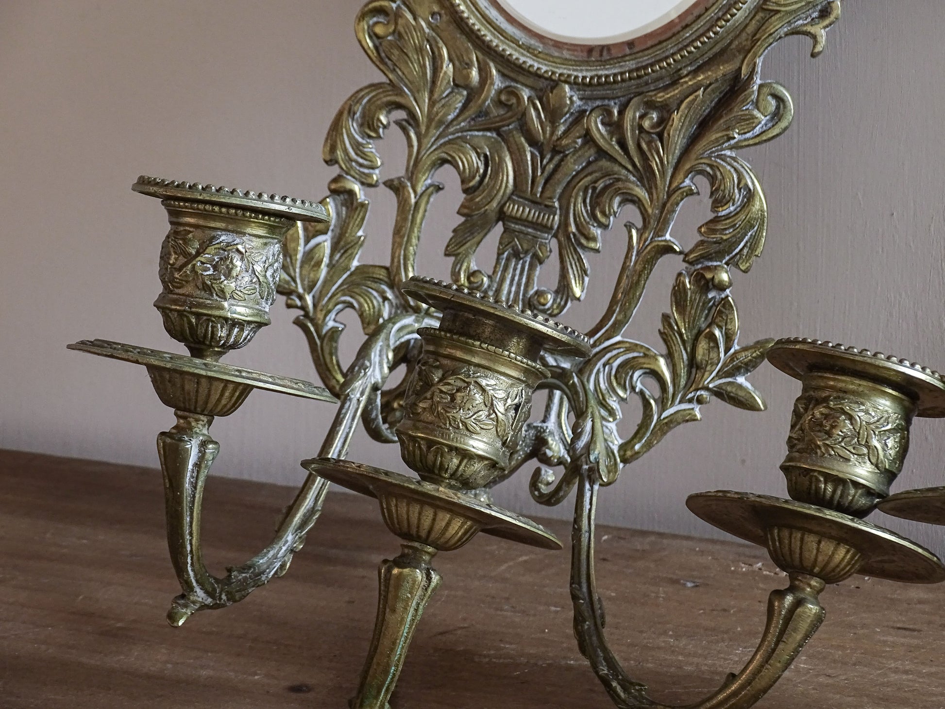Pair of French antique gilt brass candle sconces with mirrors, griffins and cherub decoration displayed together.