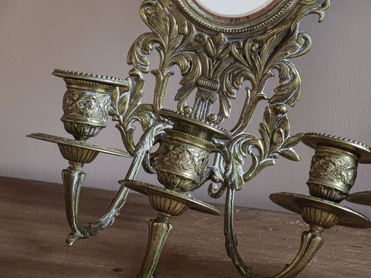 Pair of French antique gilt brass candle sconces with mirrors, griffins and cherub decoration displayed together.