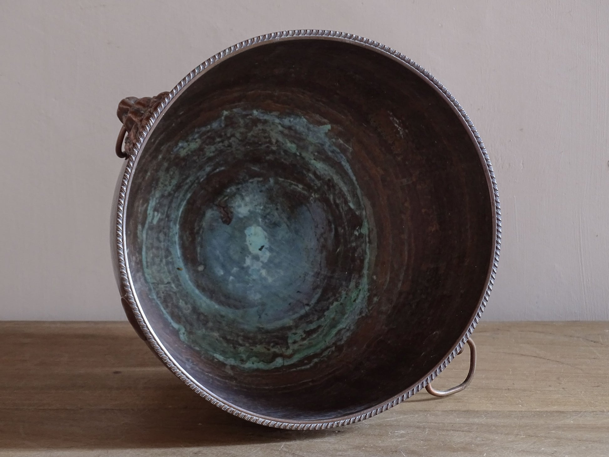 Early 20th century copper wine cooler displayed on a rustic wooden table.