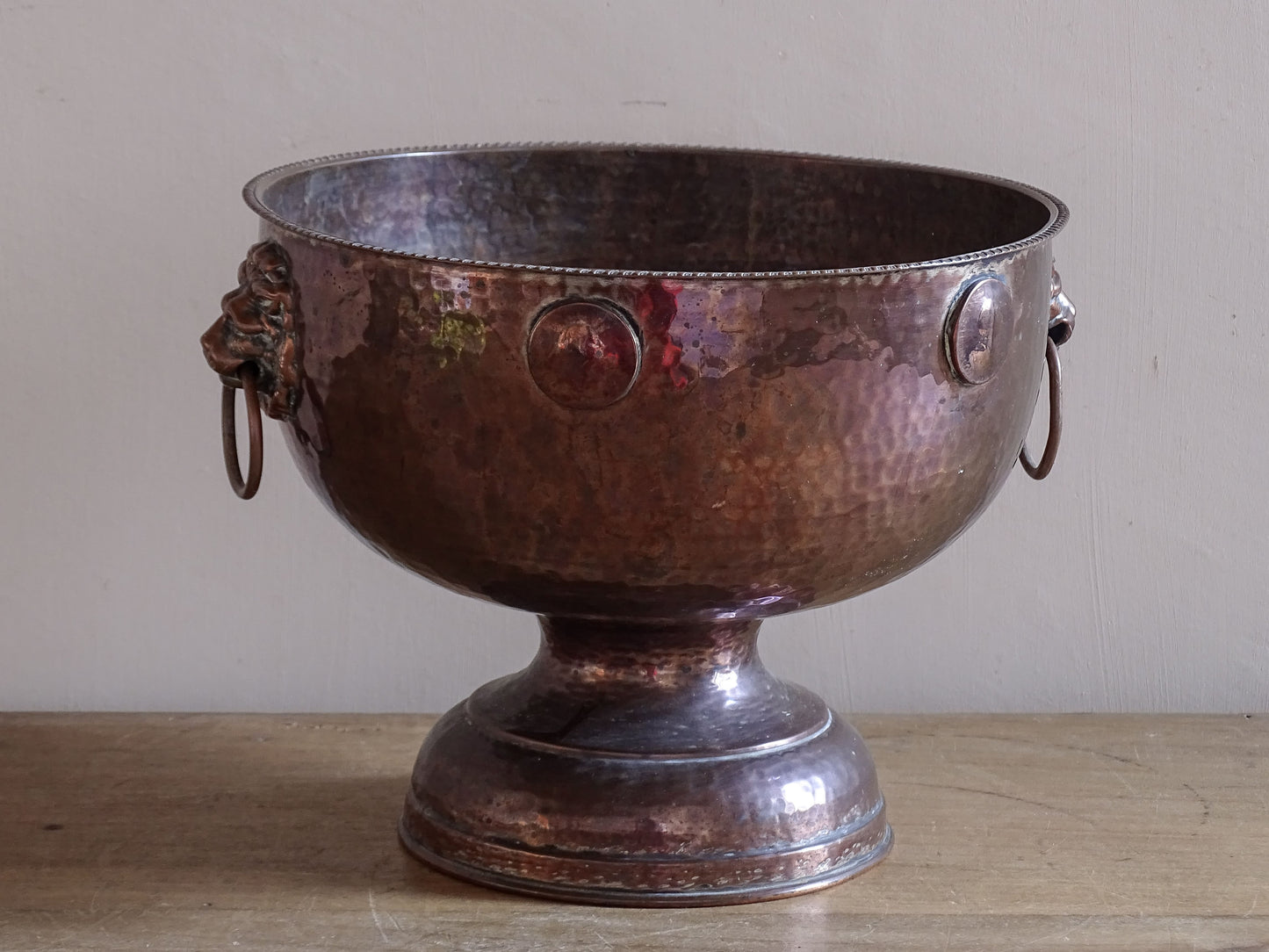 Early 20th century hammered copper champagne cooler with decorative lion mask handles.