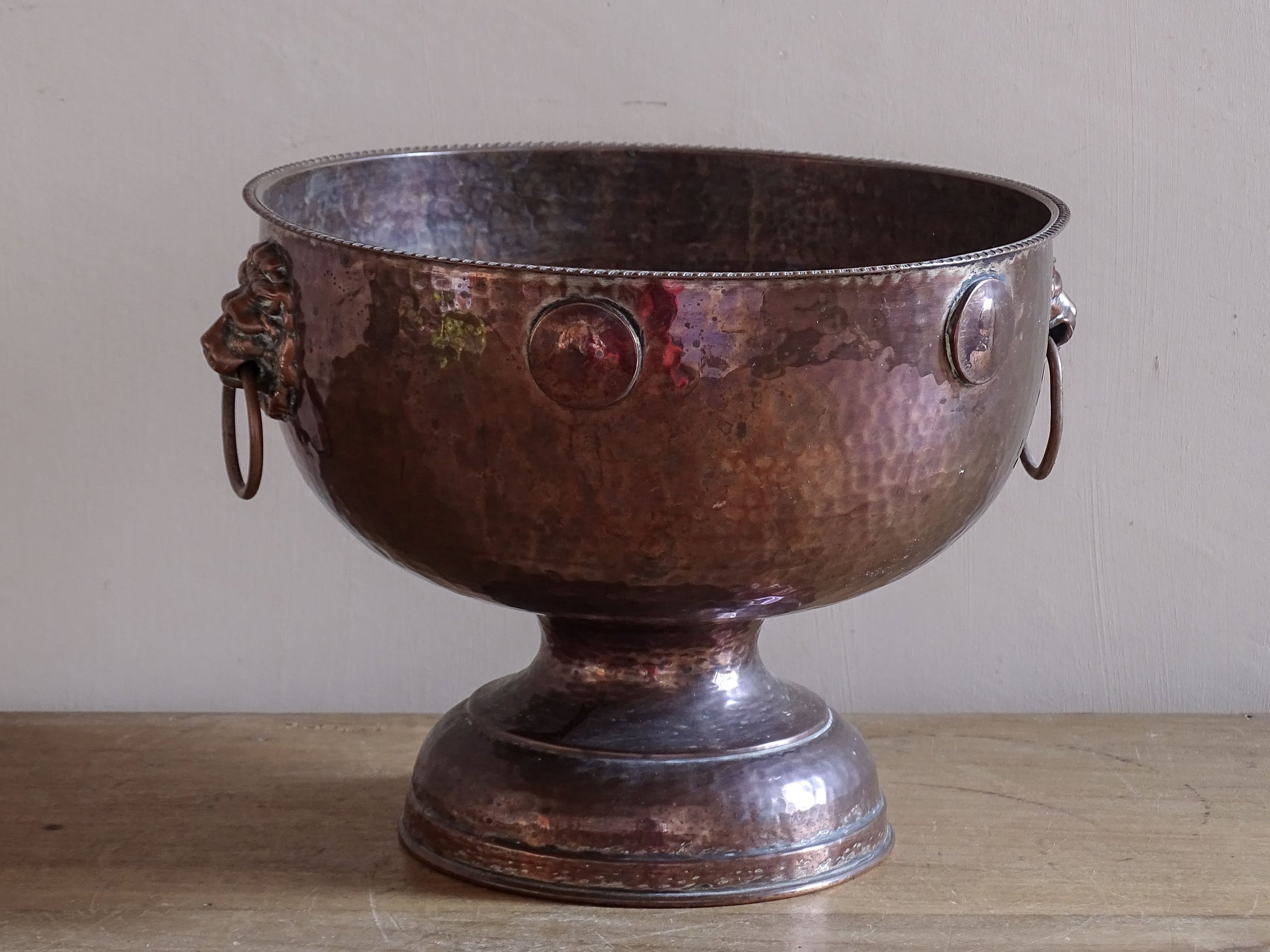 Early 20th century hammered copper champagne cooler with decorative lion mask handles.