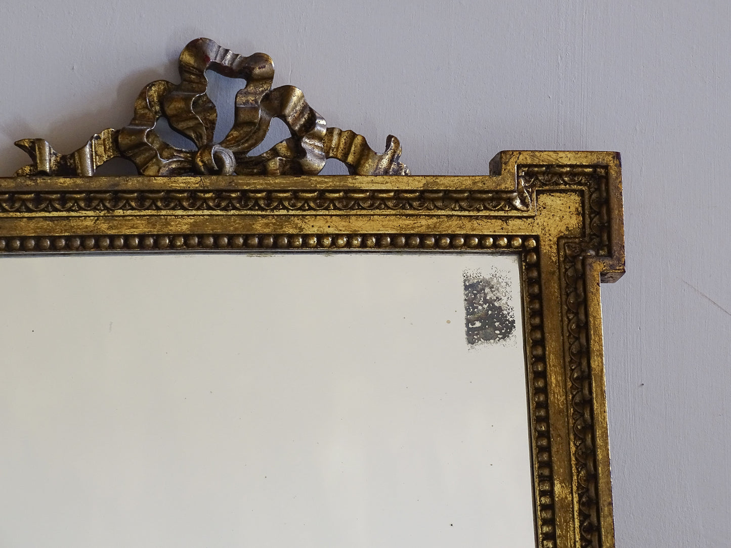 Decorative French vintage gilt mirror featuring stepped corners and aged foxed mirror plate