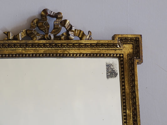 Decorative French vintage gilt mirror featuring stepped corners and aged foxed mirror plate