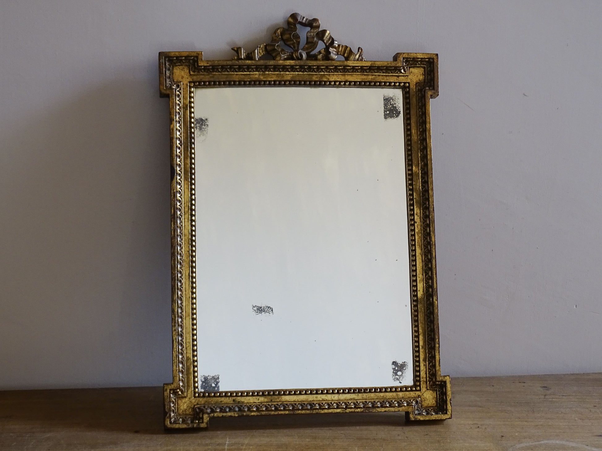 Close-up of ribbon crest detail on a vintage French gilt wall mirror