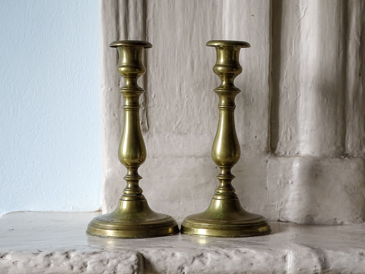 Pair of antique brass candlestick holders, pictured on a French country house fireplace