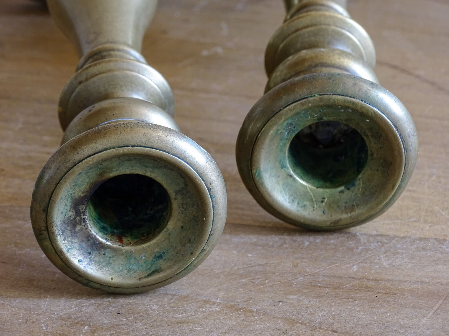 Close-up of antique brass candlestick showing aged surface and verdigris.