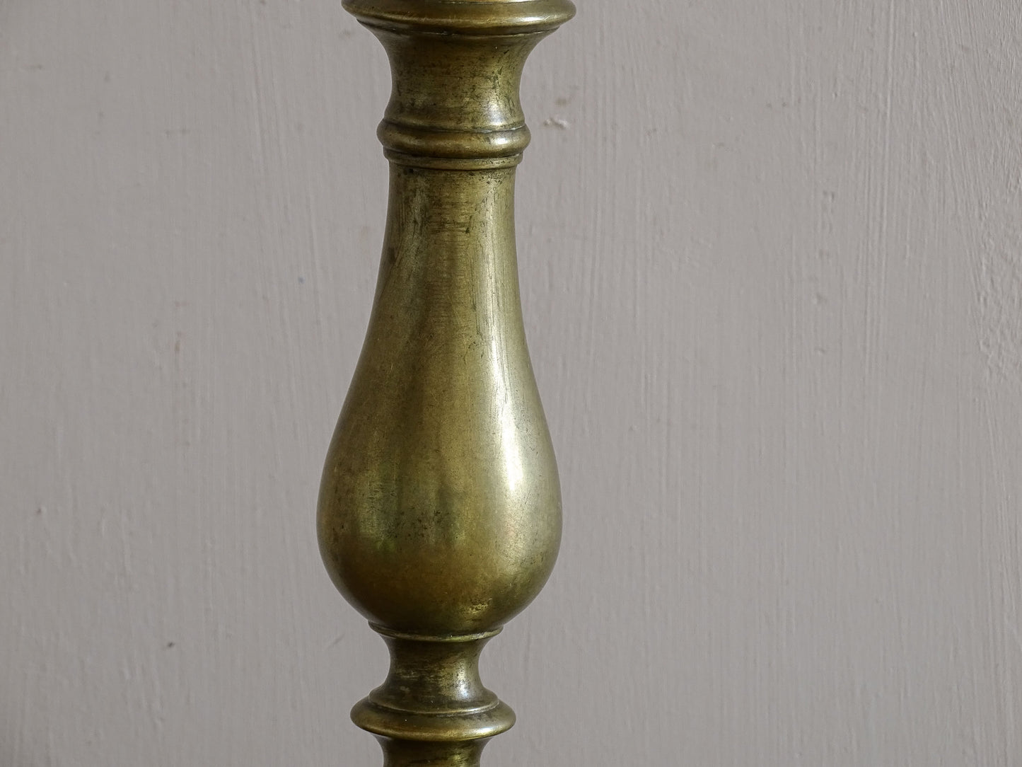 Pair of vintage brass candlesticks styled against a neutral wall.