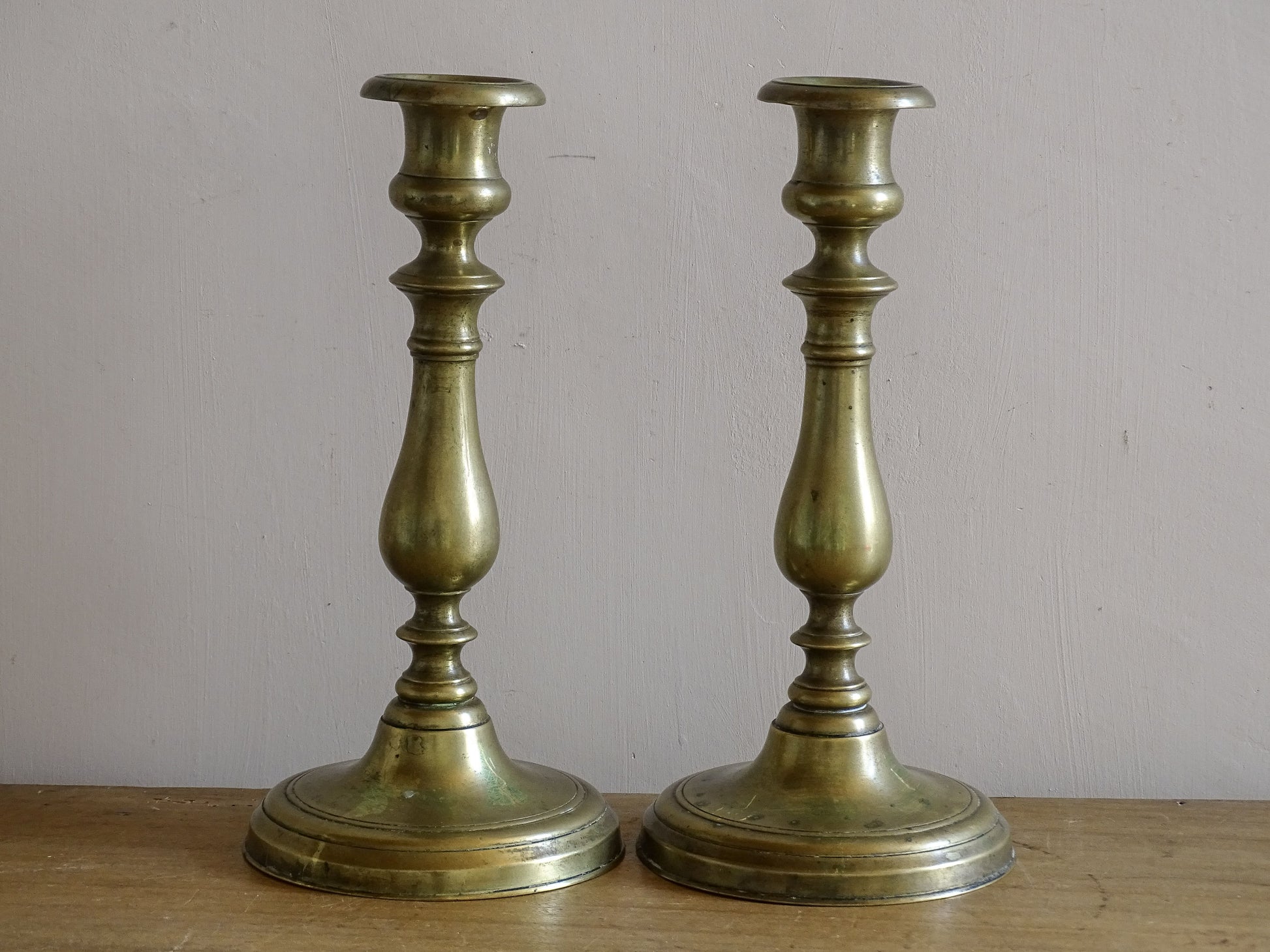 Antique brass candle holders with warm patina and stepped bases.