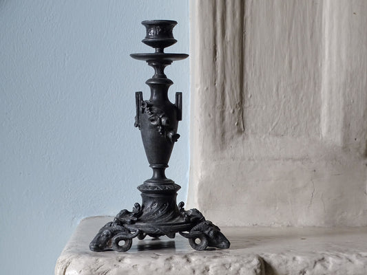 French antique candlestick with rams head, pictured on a country house fireplace.