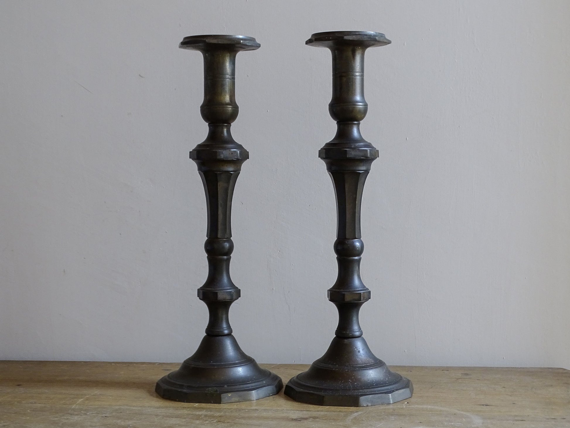 Full-length view of a matching pair of large antique candlesticks in dark patinated metal