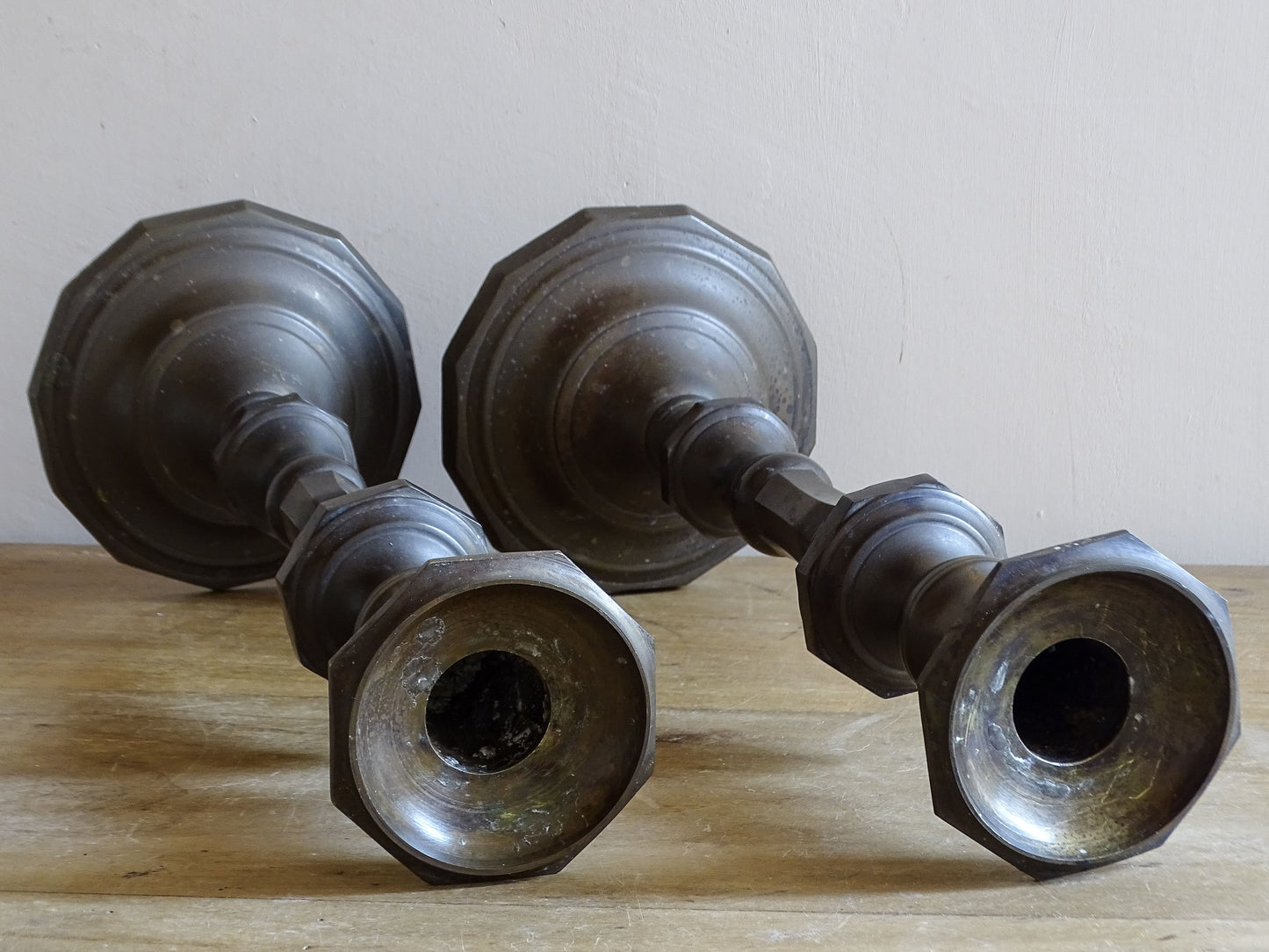 Pair of antique altar candlesticks laid on their sides showing the candle sockets and octagonal bases