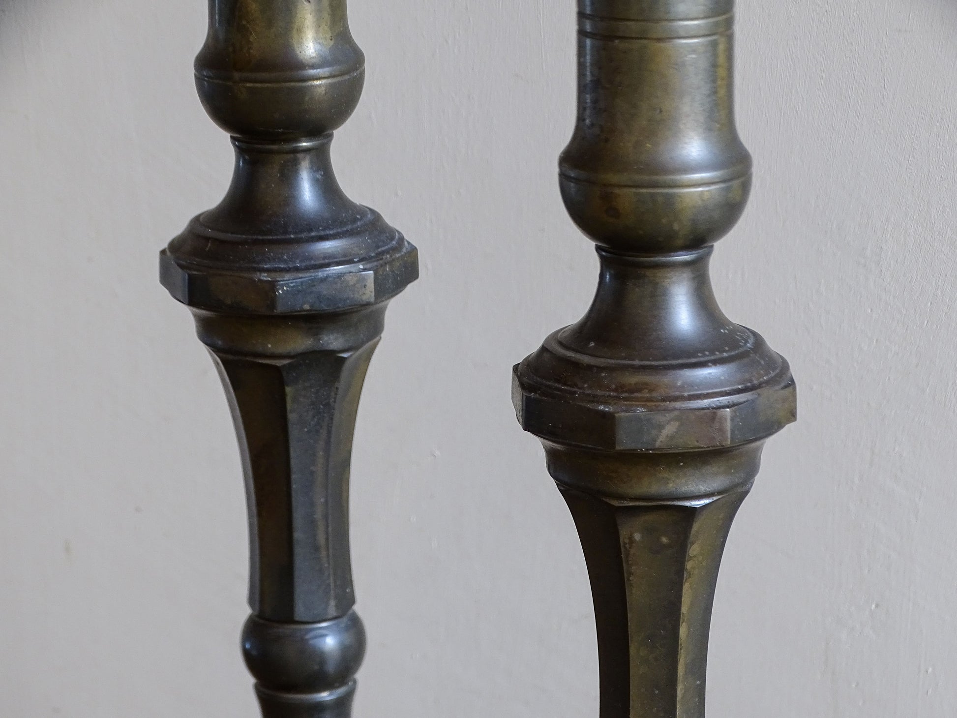 Close-up of the faceted stems and aged dark patina on two large antique candlesticks