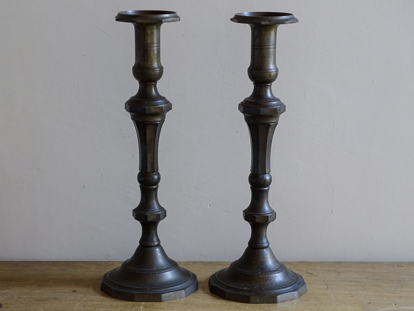 Full-length view of a matching pair of large antique candlesticks in dark patinated metal
