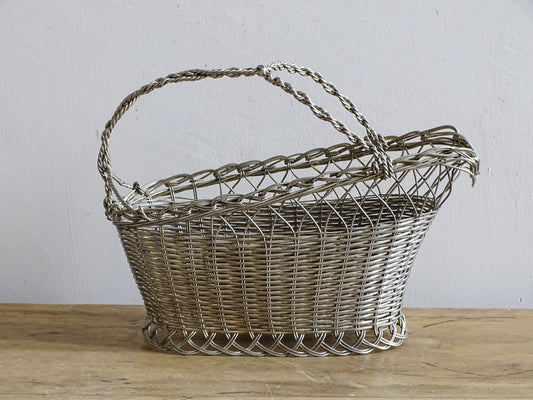 French vintage wire wine bottle carrier with twisted handle, displayed on a rustic wooden table.
