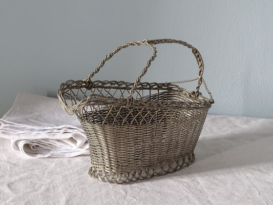 French vintage woven metal bottle basket on a country table with antique linen