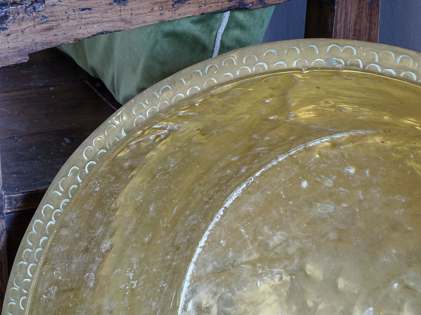 Close-up of the aged brass interior and decorative punched border on a large antique household basin.