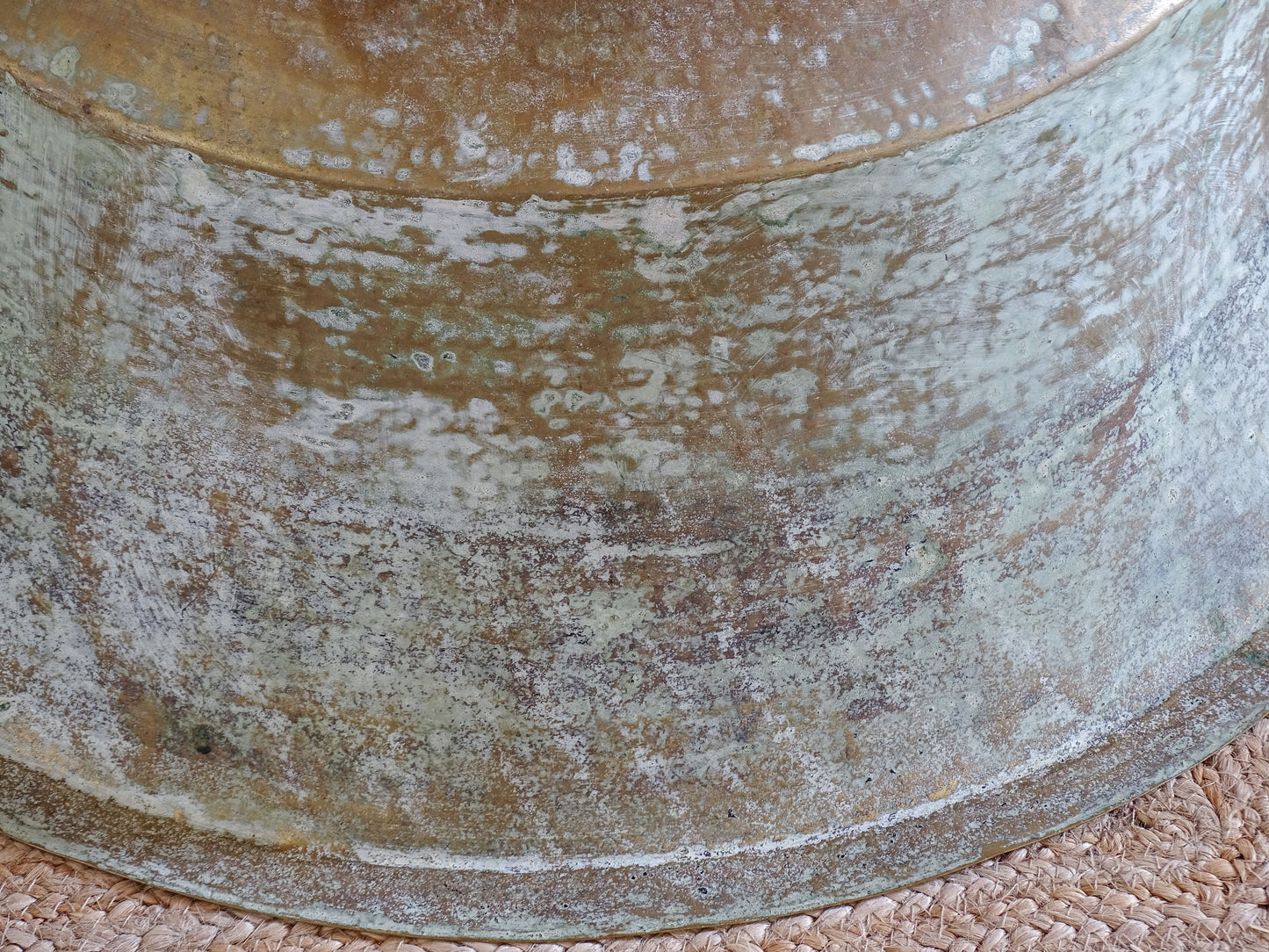 Close-up of the naturally aged green, blue and brown patina covering the exterior of an antique brass basin.