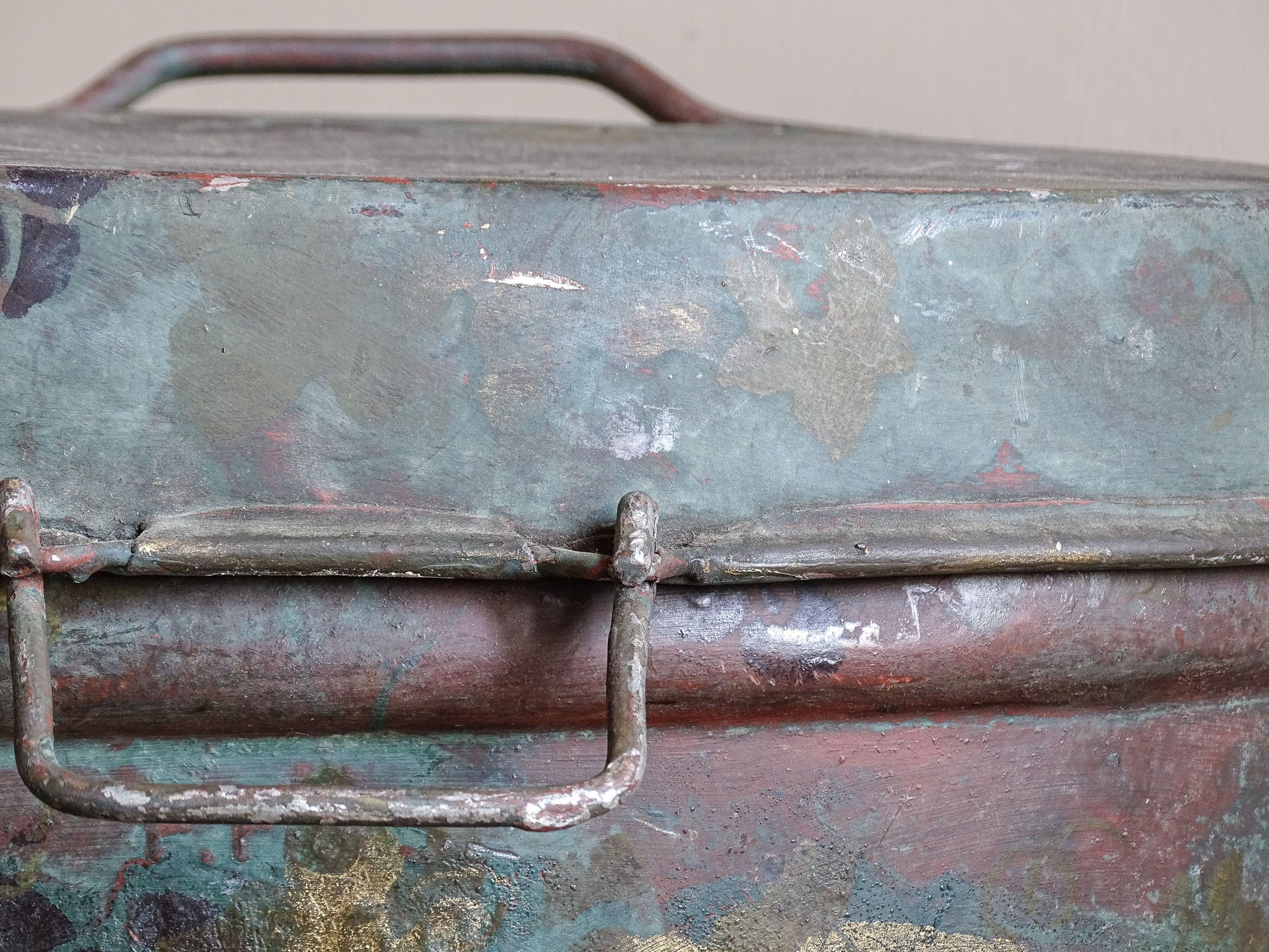 Close-up of the fitted lid and front fastening handle on a vintage painted toleware storage box.