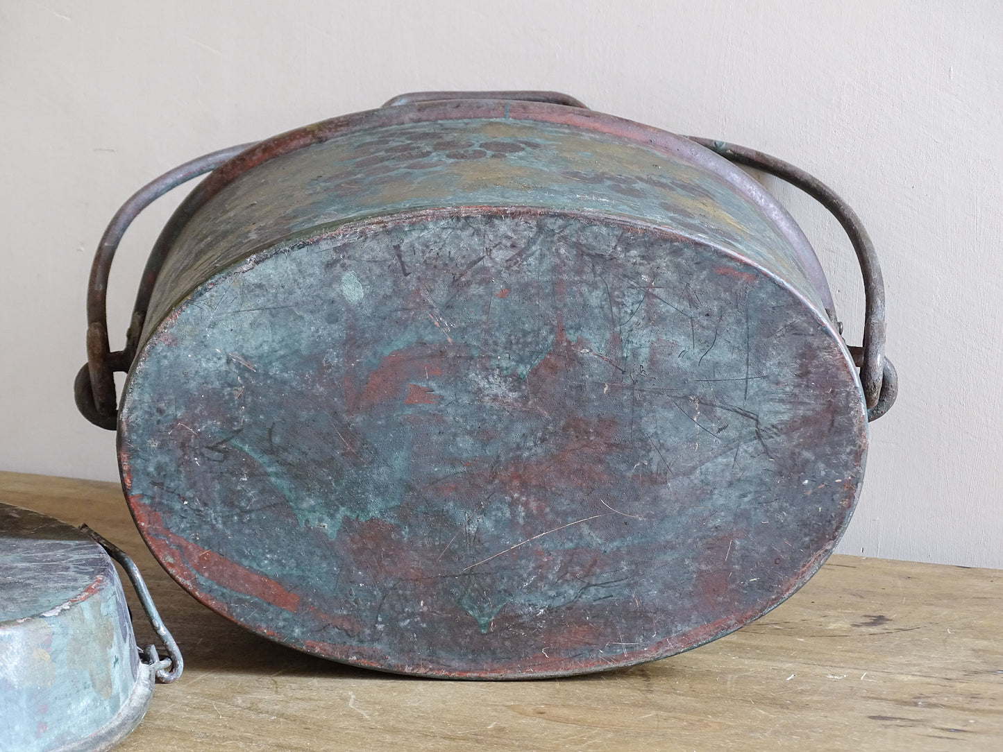 Underside of the oval vintage toleware box showing scratches, worn paint and an aged surface.