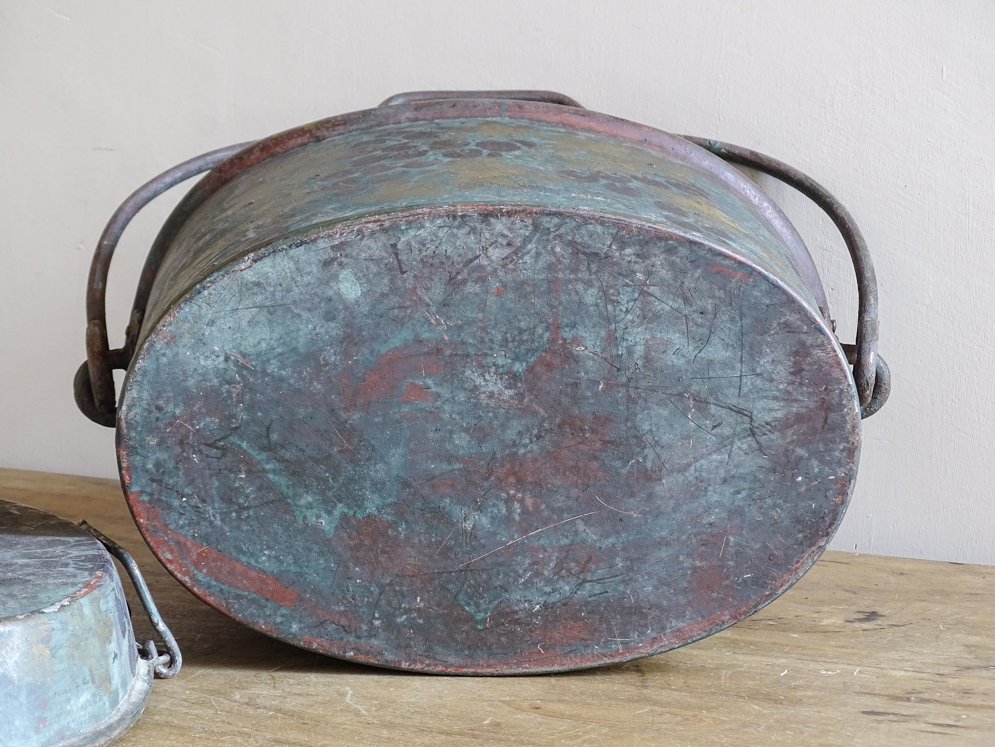 Underside of the oval vintage toleware box showing scratches, worn paint and an aged surface.