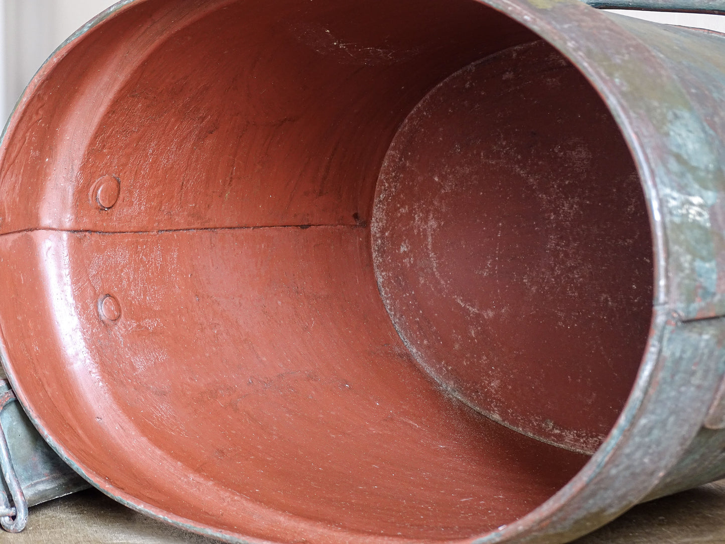 Close-up of the deep red painted interior and riveted construction of the metal storage box.