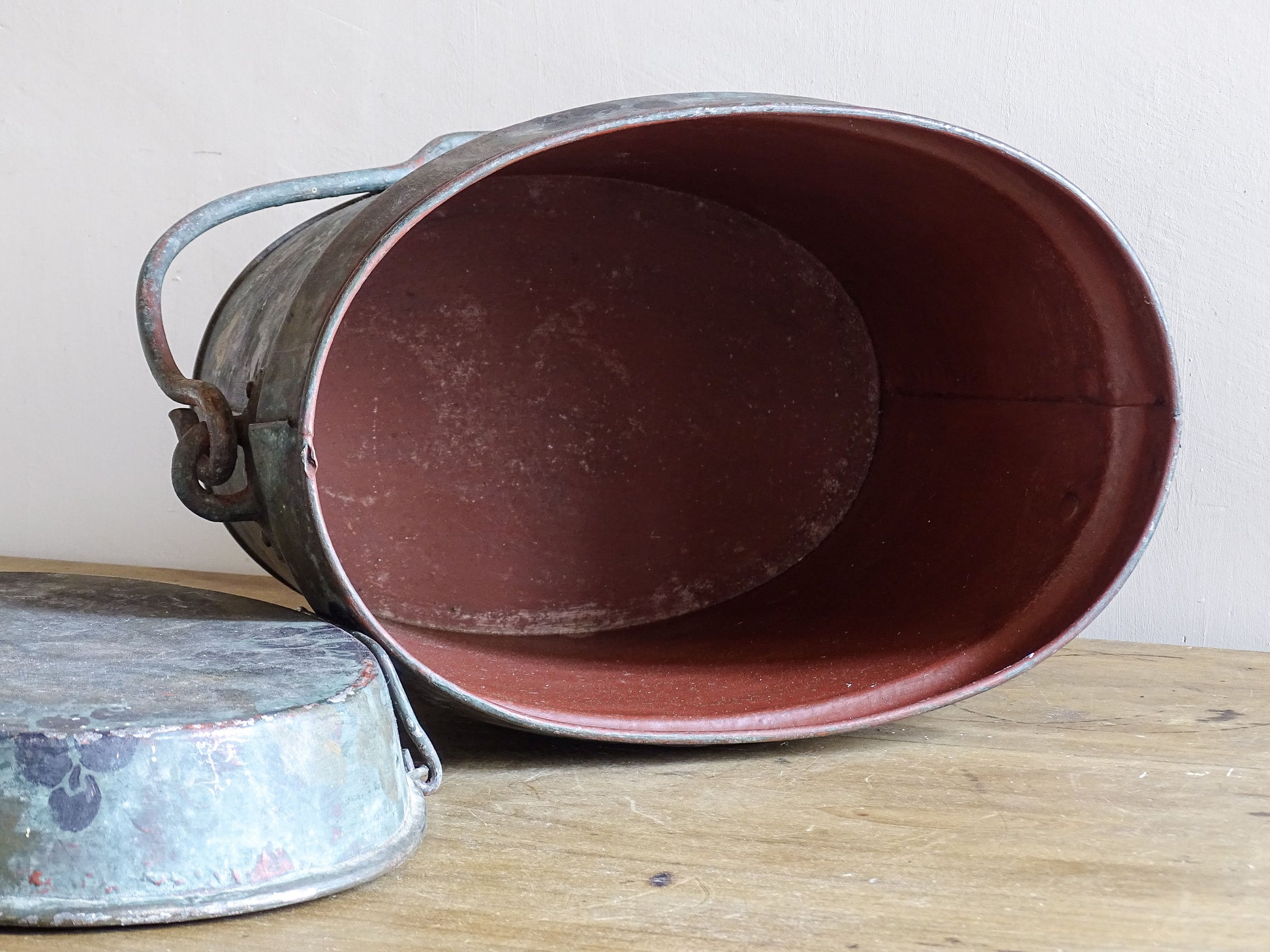 Open vintage painted metal storage box showing its oval shape, red interior and fitted lid.