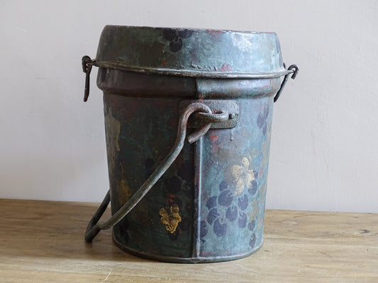 Side view of the vintage painted metal box with its broad carrying handle lowered across the body.