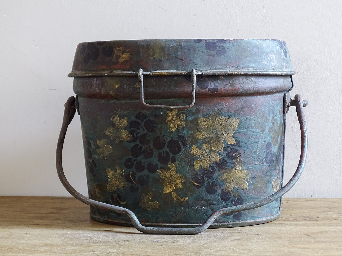 Front view of the large vintage toleware box with painted grapes, gold leaves and raised handle.