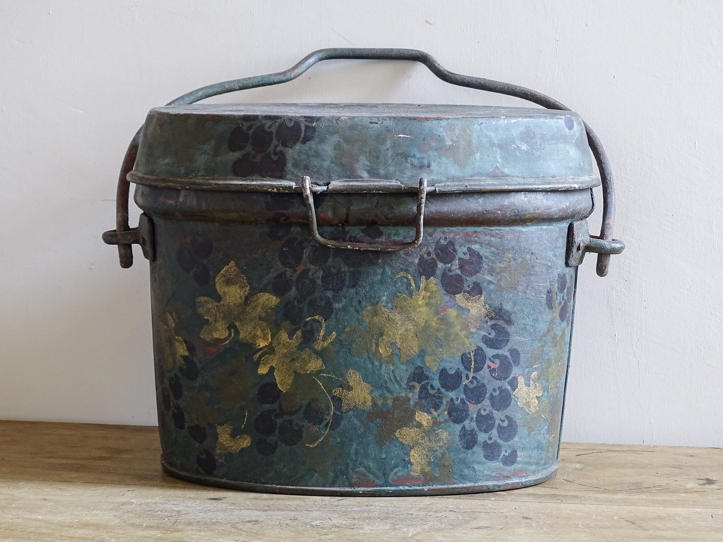 Front view of the large vintage toleware box with painted grapes, gold leaves and raised handle.