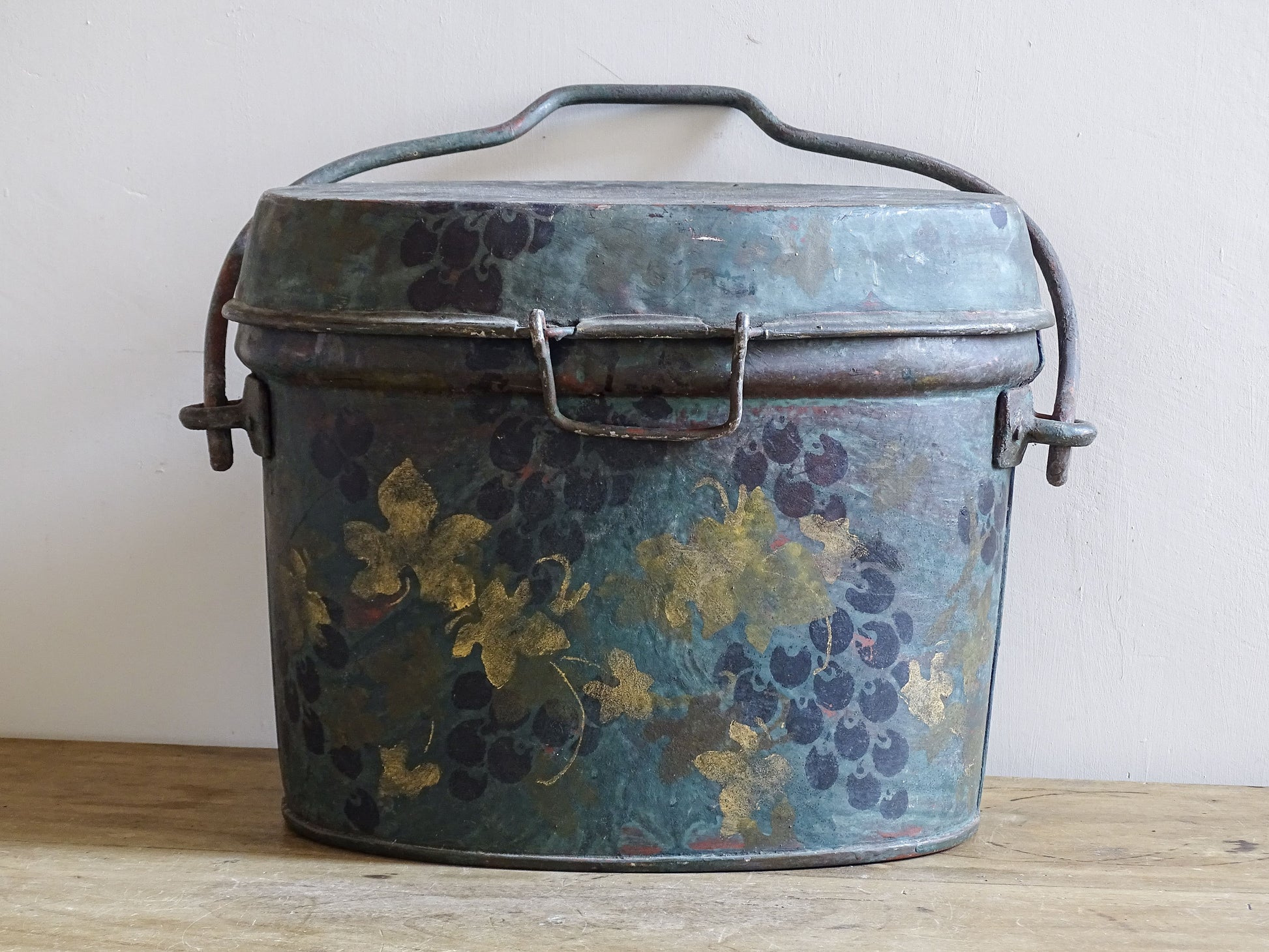 Front view of the large vintage toleware box with painted grapes, gold leaves and raised handle.