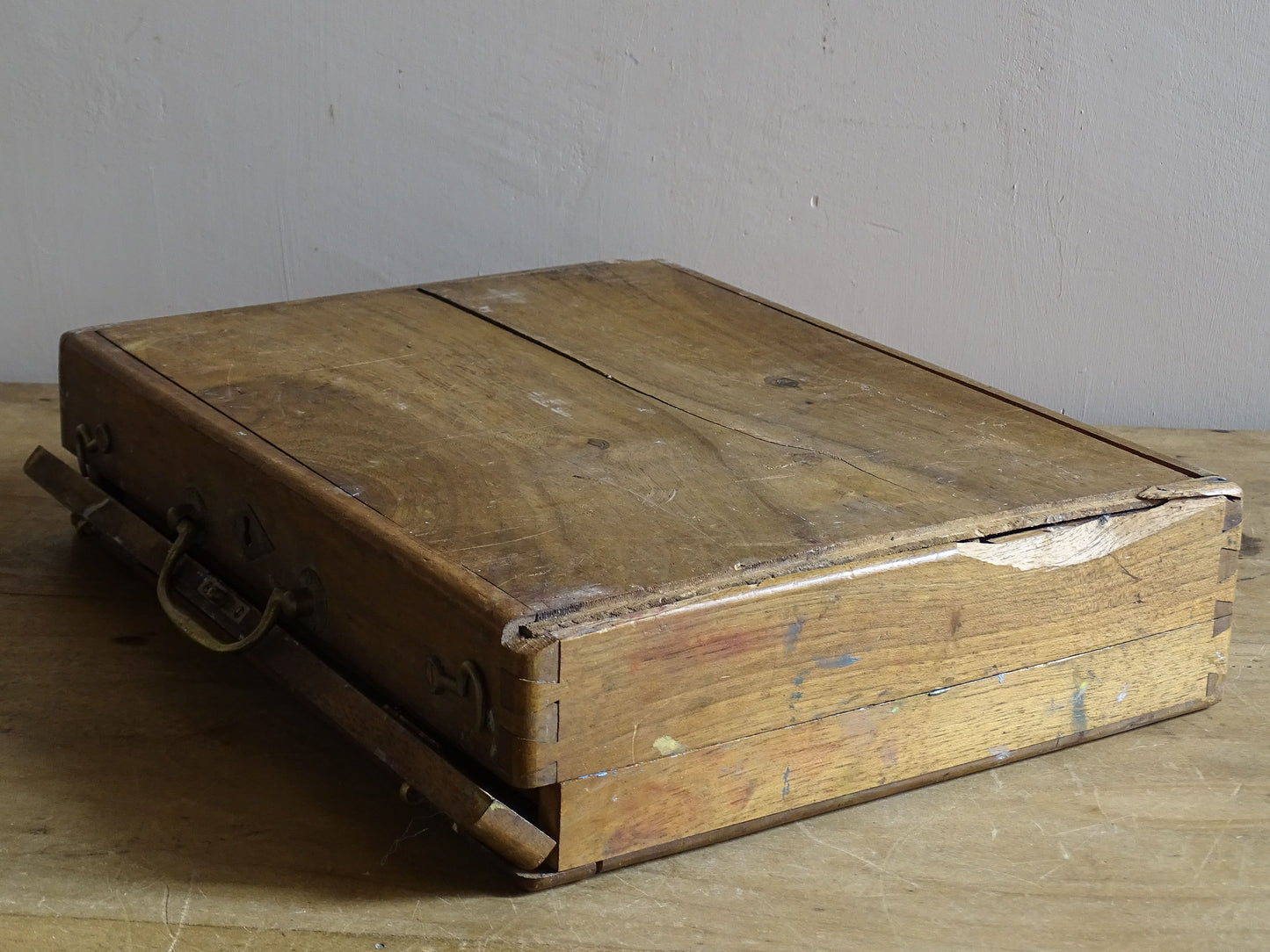 Antique artist’s paint box with aged wood, brass hardware and colourful studio residue